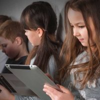 Estudantes usando dispositivos tecnológicos em sala de aula, destacando a importância do letramento em IA para que a interação com sistemas de Inteligência Artificial seja feita de maneira crítica, consciente e ética.