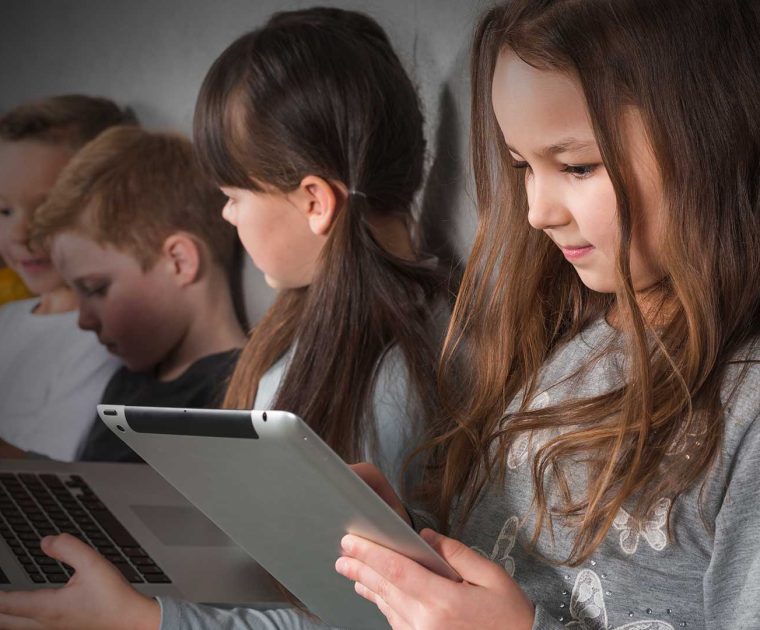 Estudantes usando dispositivos tecnológicos em sala de aula, destacando a importância do letramento em IA para que a interação com sistemas de Inteligência Artificial seja feita de maneira crítica, consciente e ética.